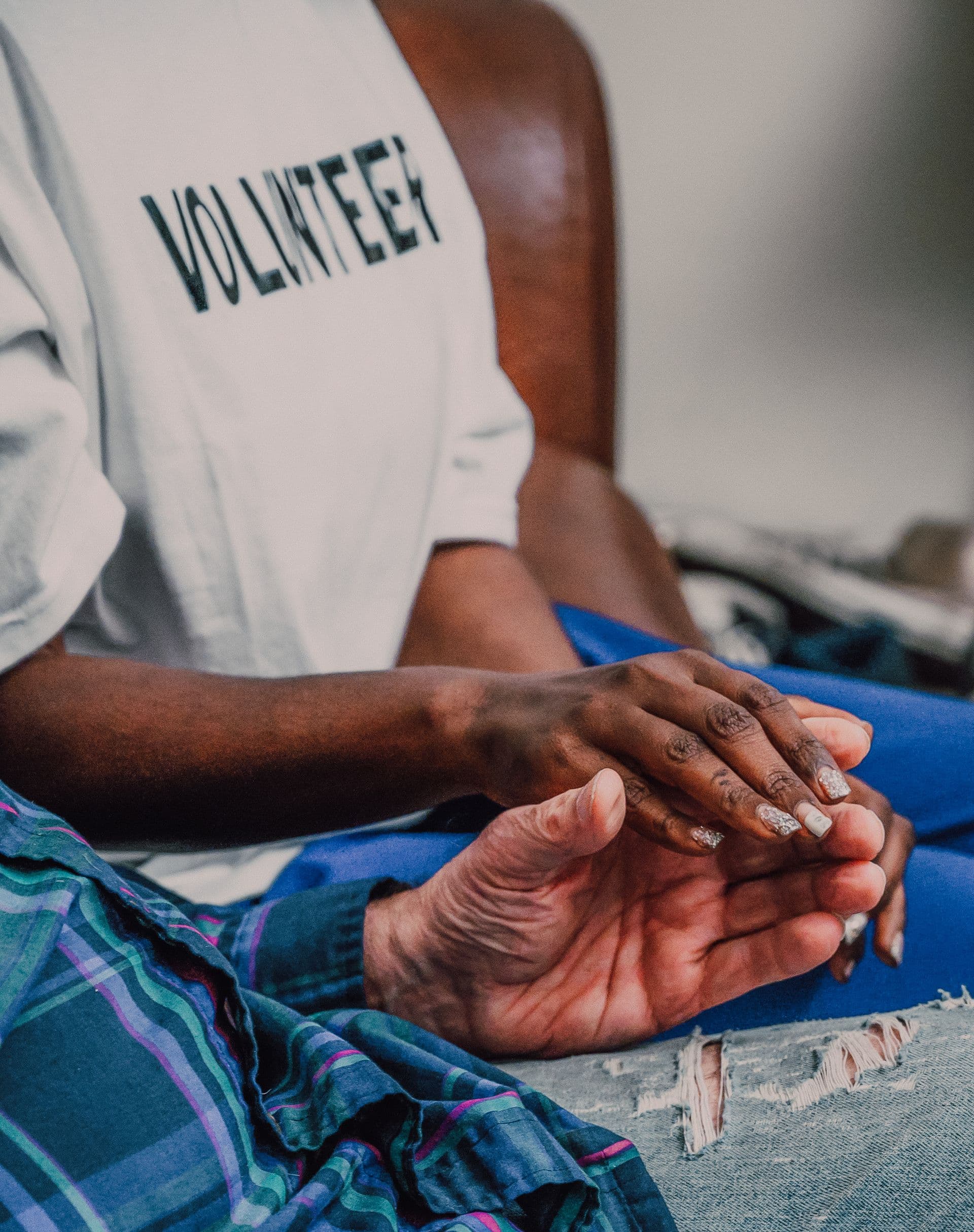 A volunteer offering comfort by holding hands with an elderly person