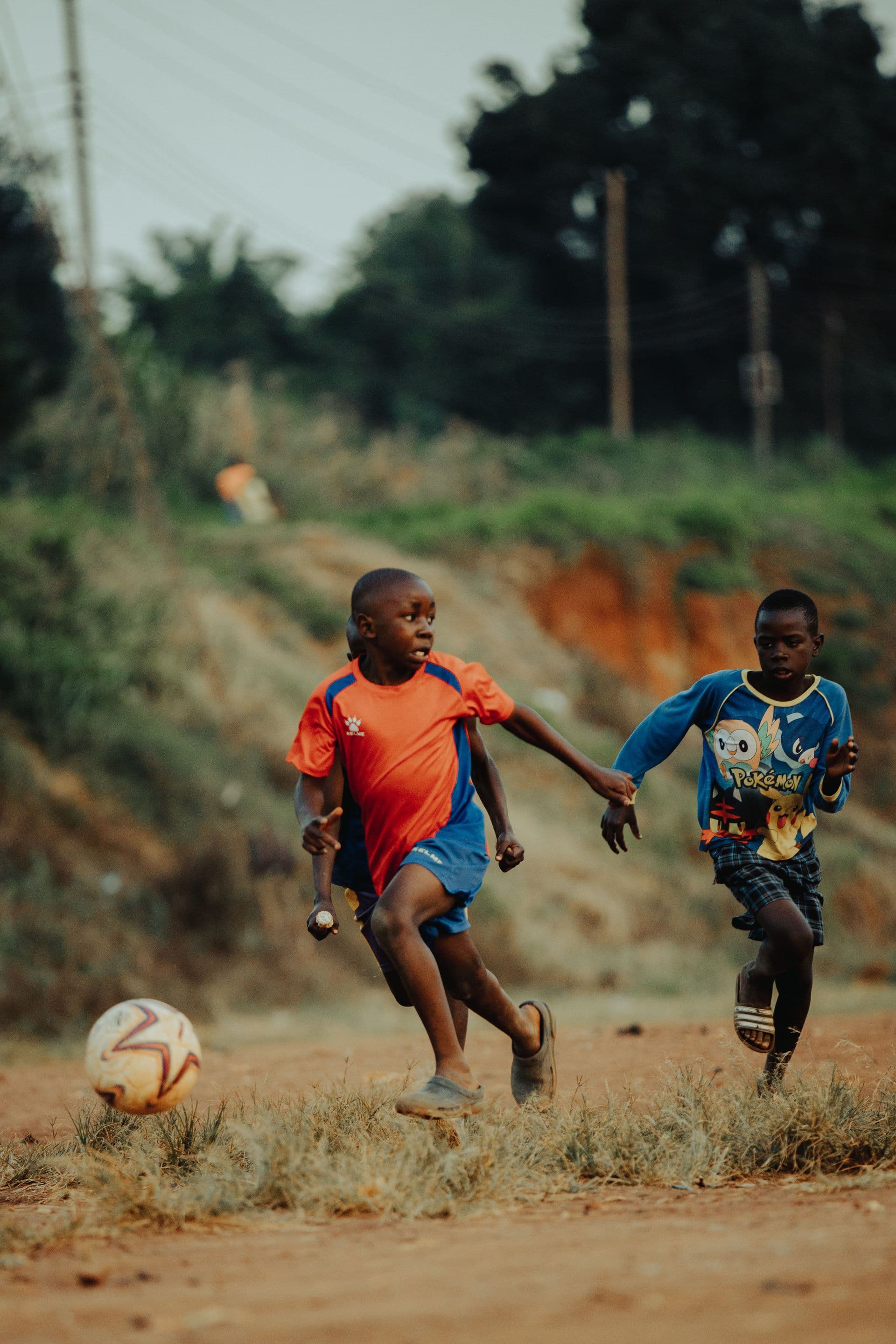 Two boys sharing a joyful moment playing football in Kampala, Uganda